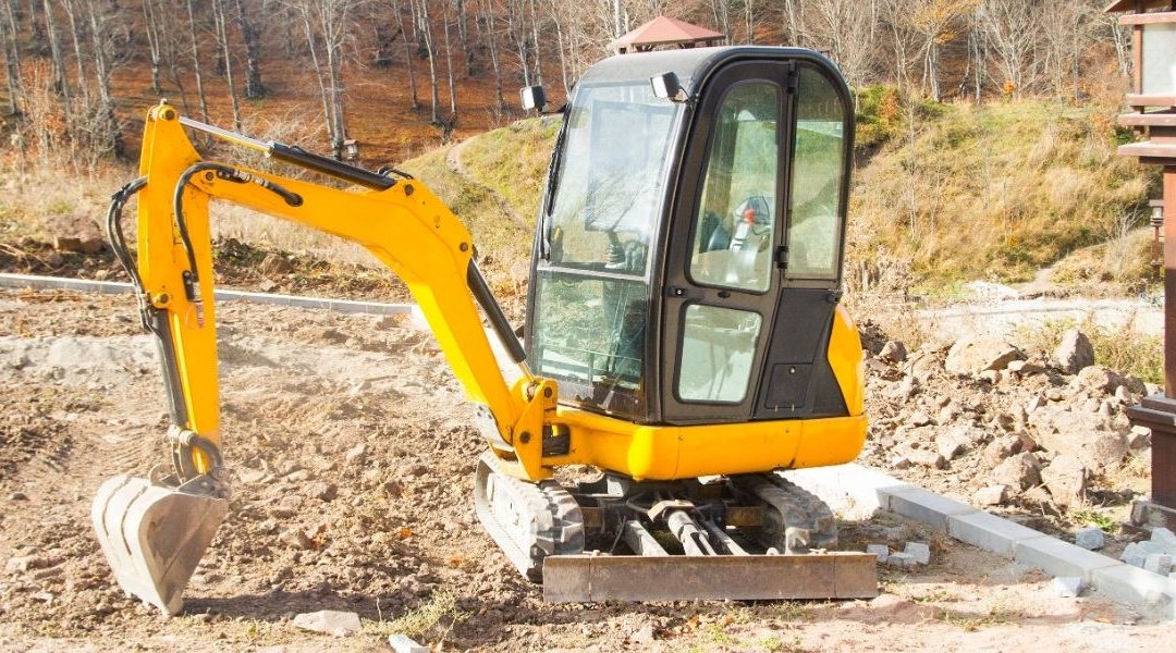 Mini excavator machine loading rear dumper truck at sand quarry during construction works.