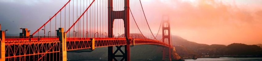 A red bridge extending across a large waterway.