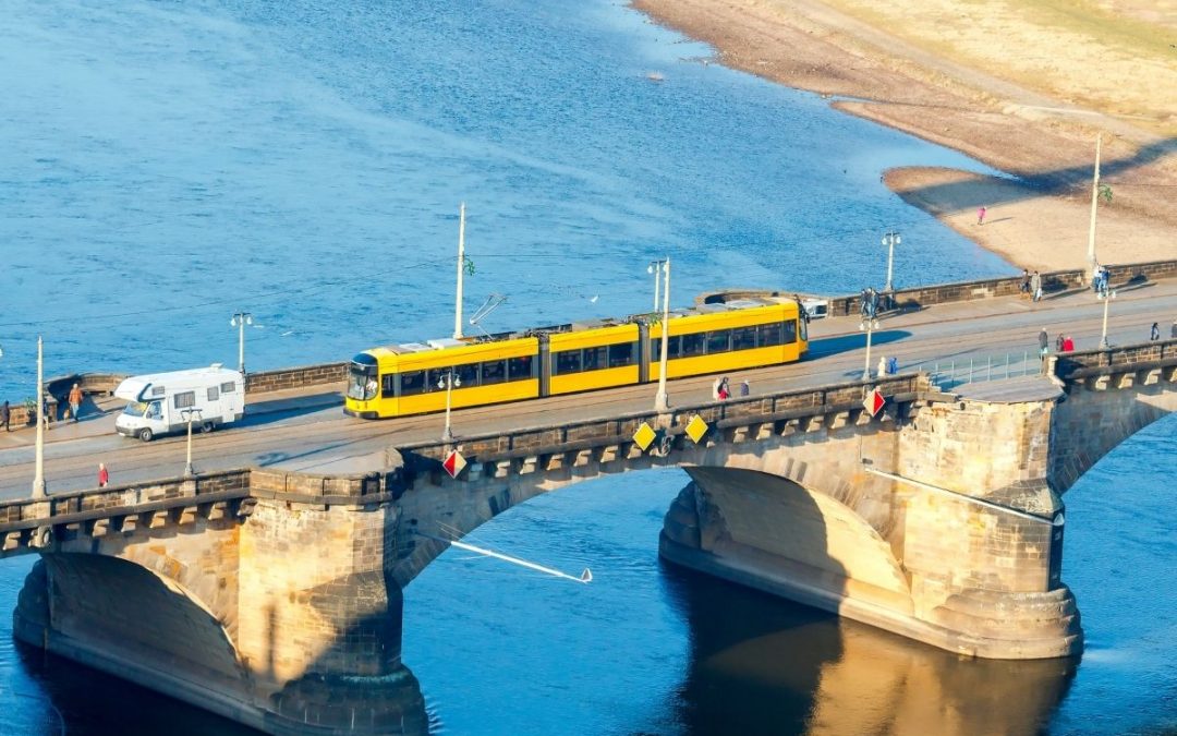 A large bus drives over a bridge.